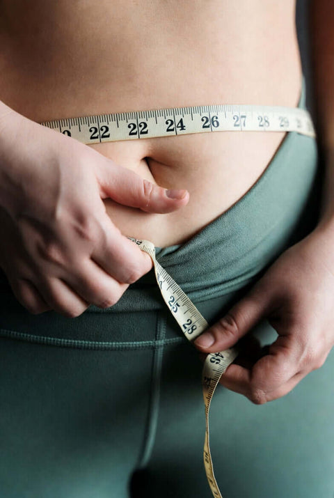 woman measuring her waist size