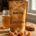 ROOTFUL ACV & Kombucha Gummies pouch next to apple cider vinegar jar and cinnamon sticks, golden gummies scattered on wooden surface