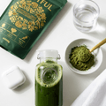 ROOTFUL Superblend greens and superfoods powder 300g with green juice drink, powder scoop in bowl and glass of water flat lay on white surface