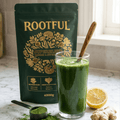 ROOTFUL Superblend greens and superfoods powder 300g with freshly mixed green smoothie drink, lemon, ginger and powder scoop on marble surface