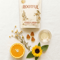 ROOTFUL Vitamin D3 gummies flatlay with orange slice, sunflower, wildflowers and gummies on white background, top-down view